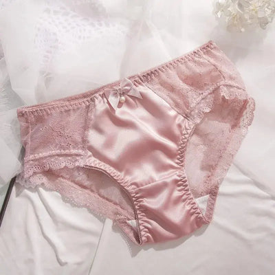 Pink satin panties with sheer floral lace sides and pearl bow detail, flat lay