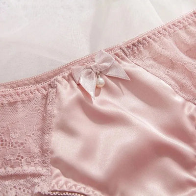 Close-up of pink satin panty center with ribbon bow and dangling faux pearl
