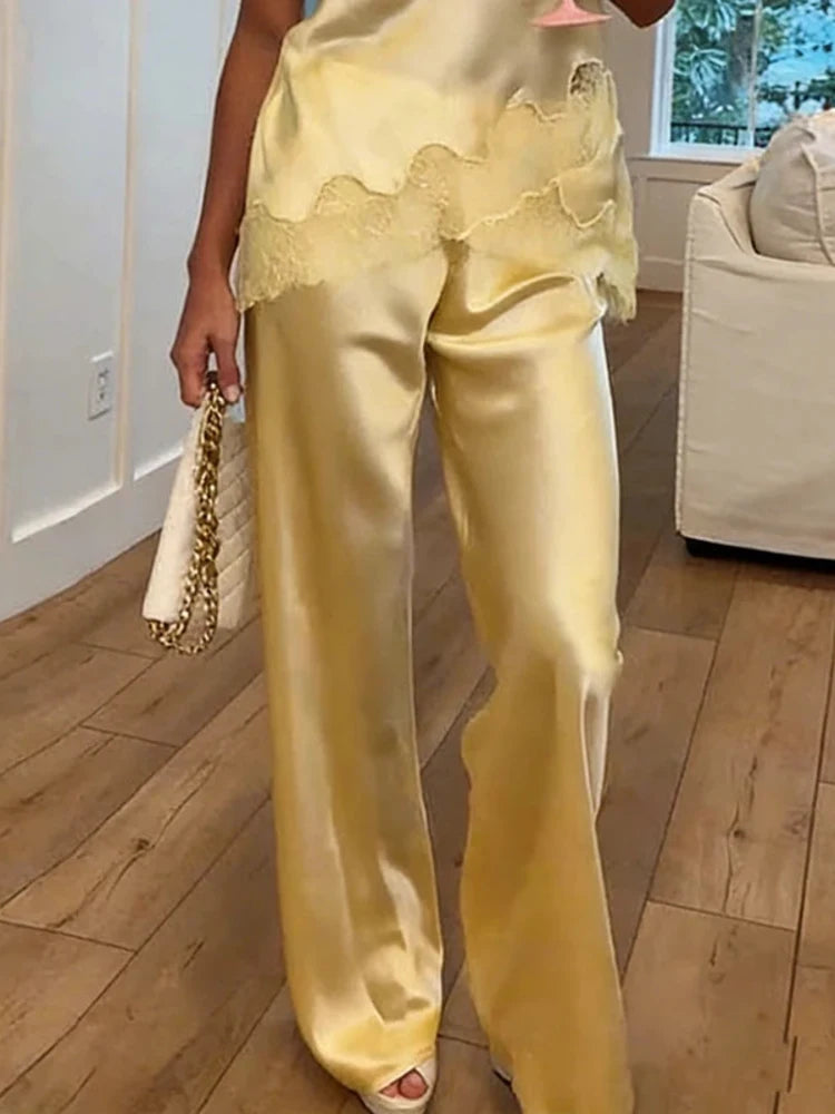 Yellow satin wide-leg pants with scalloped lace waistband trim worn with matching cami top and heels