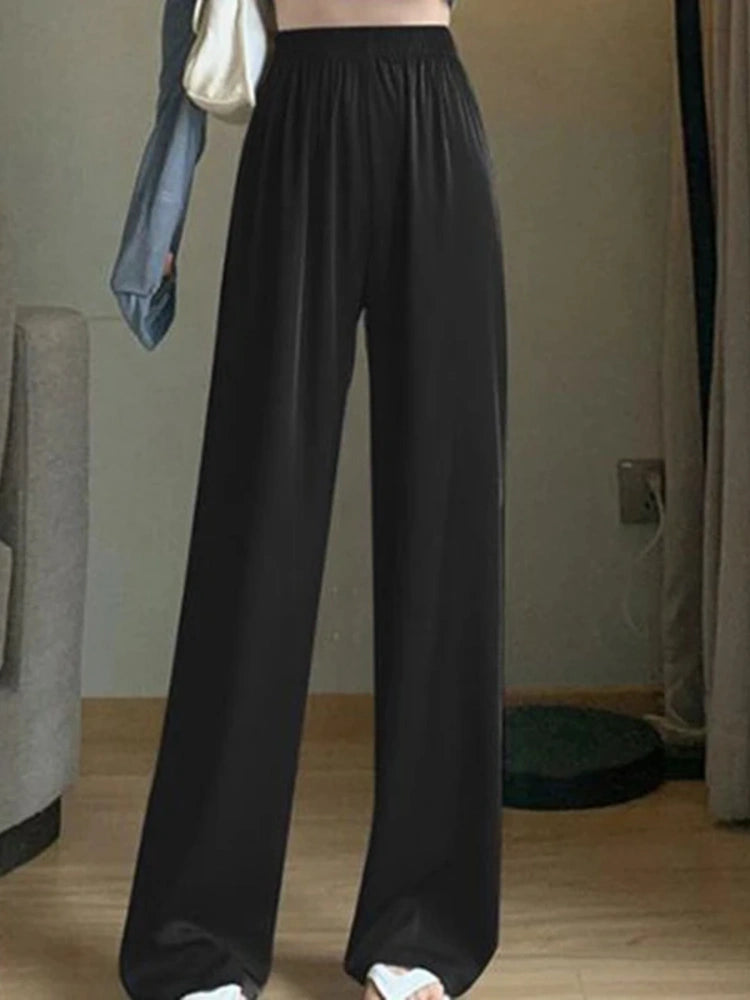 Black high-rise wide-leg pants with elastic waistband and floor-length fluid drape, front view