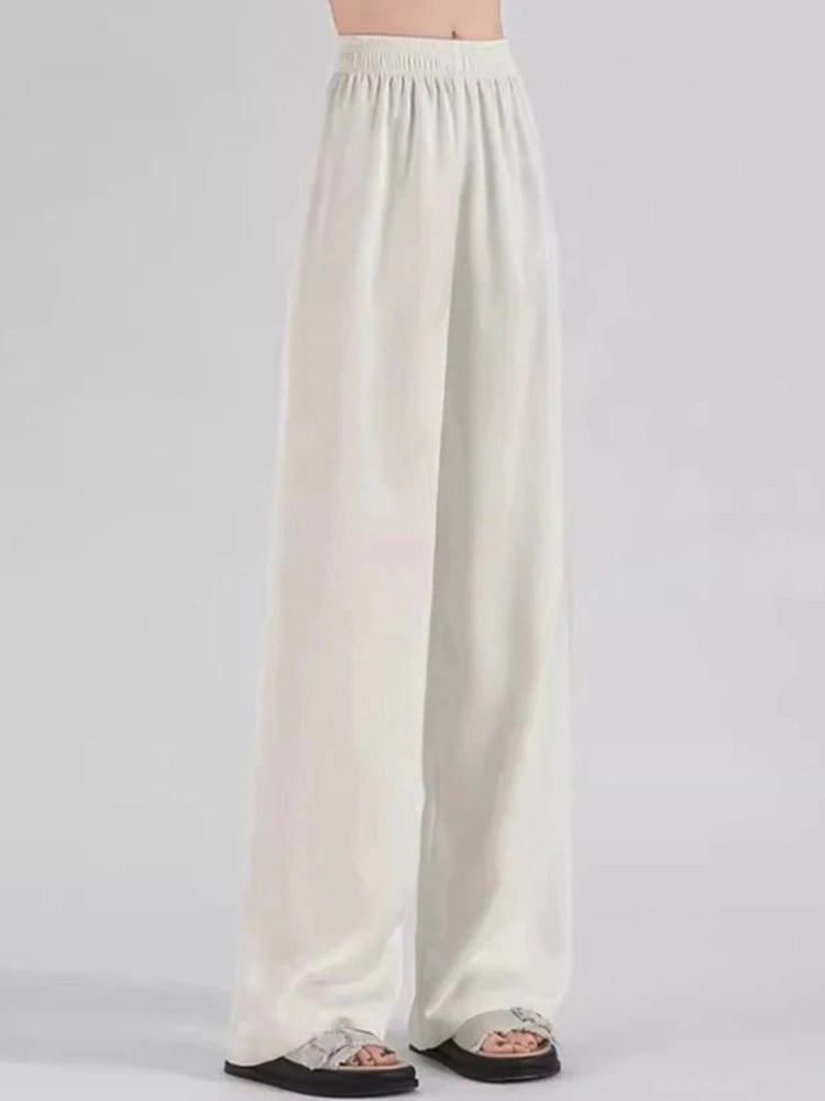 White wide-leg high-waist satin pants with smocked waistband worn with white sneakers