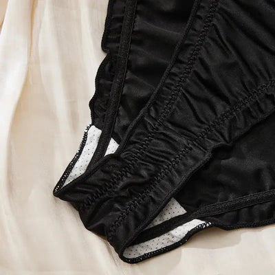 Close-up of black satin ruched panty showing cotton gusset lining and elasticized leg edge detail