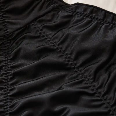 Close-up of black satin fabric showing ruched texture and smocked stitching detail on panty exterior