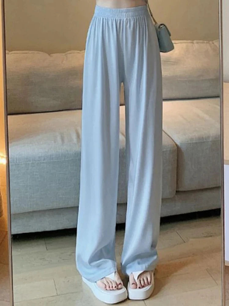 Light blue wide-leg satin pants with smocked waist worn with white platform sandals