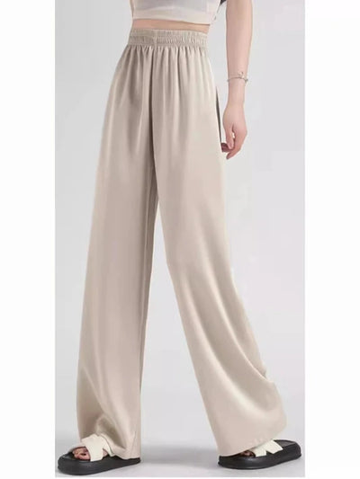 Side view of beige smocked-waist wide-leg satin pants with fluid floor-length silhouette