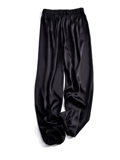 Flat lay of black high-shine tapered pants showing elastic waist and gathered ankle cuffs