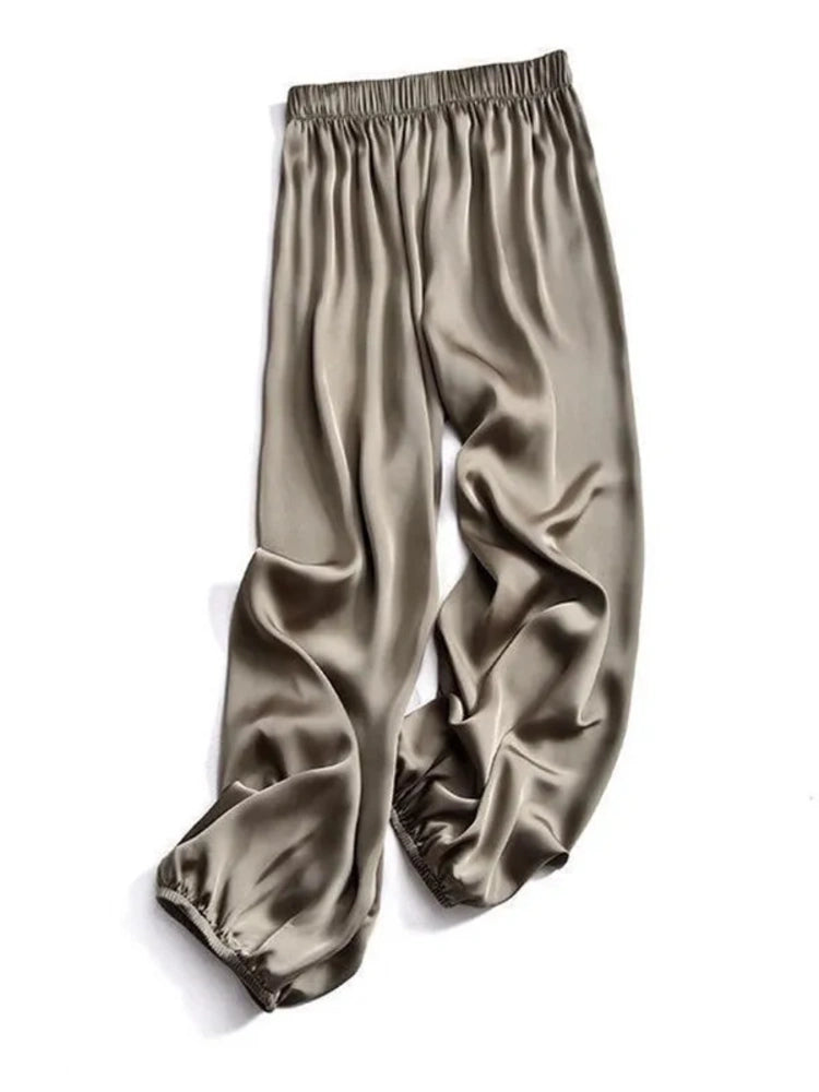 Flat-lay of khaki satin jogger pants with elastic waistband and gathered ankle cuffs
