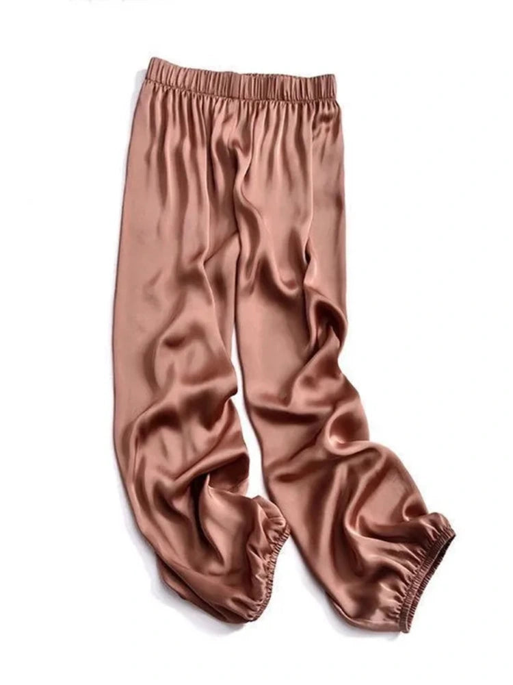 Flat-lay of dusty rose satin jogger pants with elastic waistband and gathered ankle cuffs