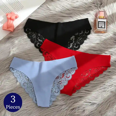 Three lace-trim satin panties flat lay in black, red and periwinkle blue with perfume bottle