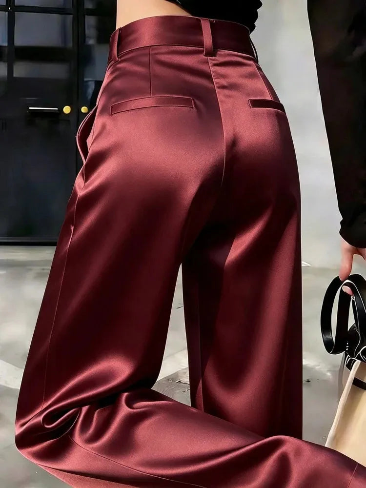 Back view of bordeaux high-waist wide-leg satin pants with welt pockets and floor-length drape