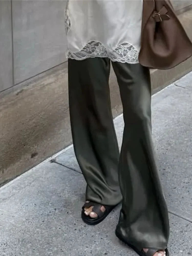 Olive green flared satin pants with lace trim, styled with sandals and a brown bag