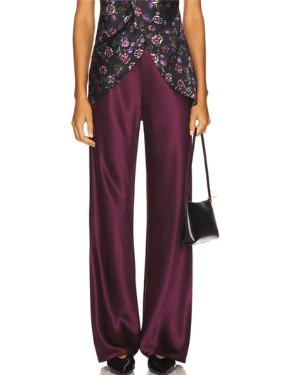 Close-up of deep burgundy wide-leg satin pants styled with a floral printed top and a small black shoulder bag