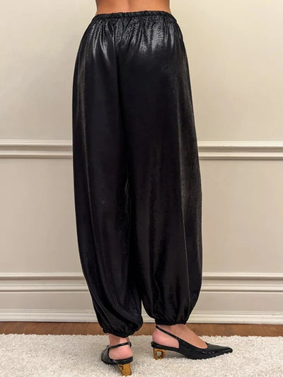 Back view of black high-shine balloon-leg pants with elasticized ankle cuffs and slingback heels