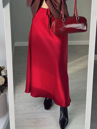 Red satin midi skirt styled with brown knit, red patent bag, black heeled boots, mirror selfie
