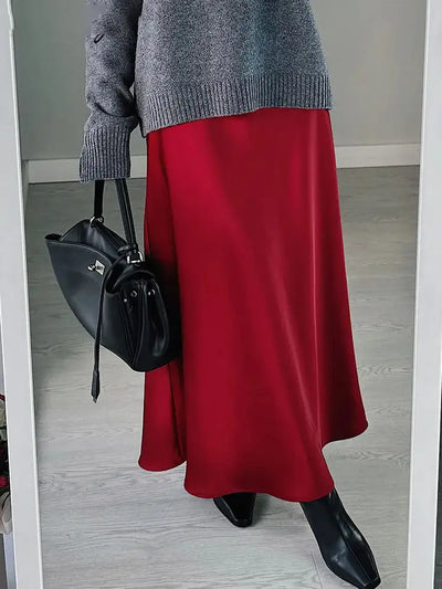 Red satin midi skirt with gray oversized sweater, black structured bag, black heeled boots