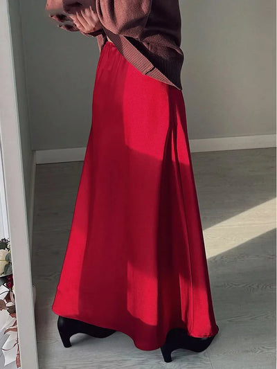 Side view of red satin A-line midi skirt with brown knit top and black heeled boots