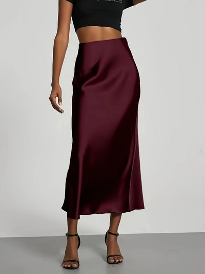 Burgundy high-waist satin midi skirt with glossy finish, worn with black crop top and heeled sandals