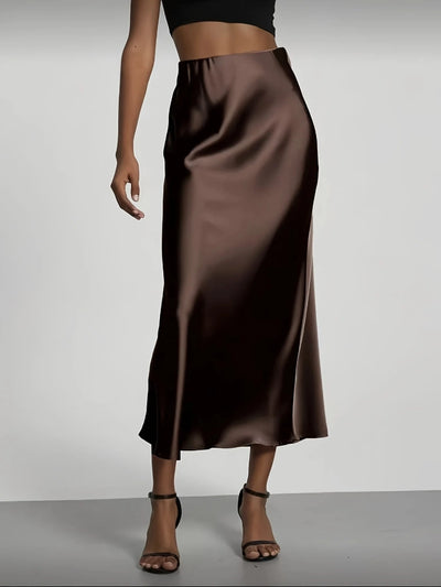 Dark brown high-waist satin midi skirt with glossy A-line silhouette, black crop top, strappy sandals