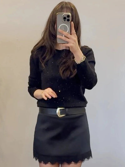 Mirror selfie showing black sparkle sweater tucked into a black lace-hem mini skirt with western belt