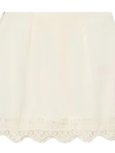 Flat lay of ivory satin mini skirt with scalloped white lace trim and visible side zipper