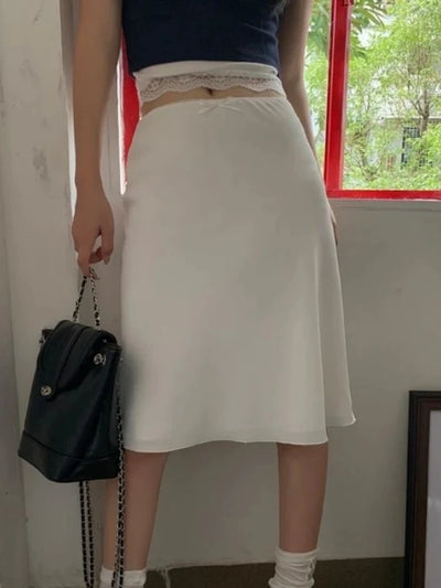 White A-line midi satin skirt with lace trim waist, model holding black chain bag