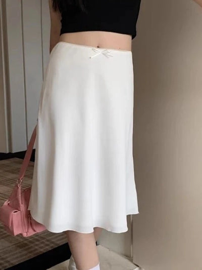 White midi satin skirt with ribbon bow waistband, side view with pink shoulder bag