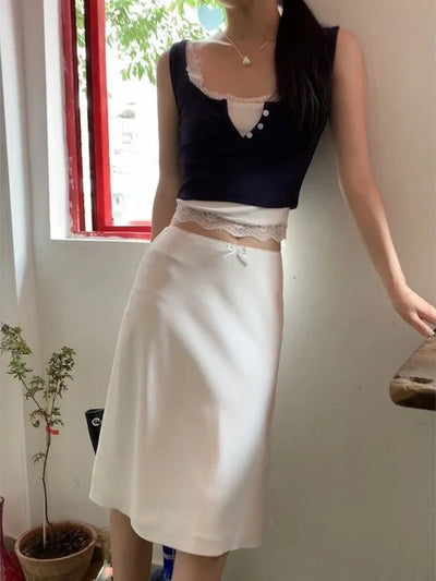 Full front view of white lace-waist midi satin skirt paired with navy sleeveless crop top