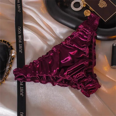 Burgundy gathered satin bikini panties with gold coin charm on white satin fabric