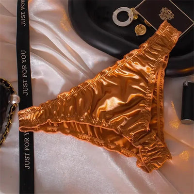 Gold gathered satin bikini panties with ruched waistband on white satin fabric