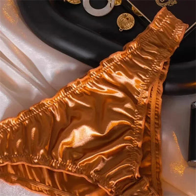 Close-up of gold satin panties showing ruched waistband and high-shine finish