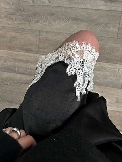 Close-up of ivory floral lace hem on black velvet midi skirt held in hand showing detail