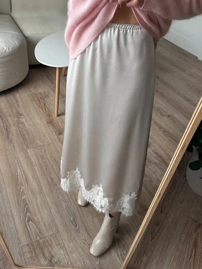 Ivory fluid midi skirt with white lace hem worn with pink sweater and cream ankle boots