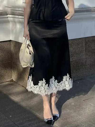 Black satin midi skirt with white floral lace hem worn outdoors with black top and silver flats