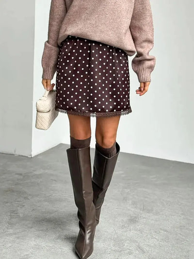 Close-up of brown polka dot satin mini skirt with black lace hem trim and mauve sweater