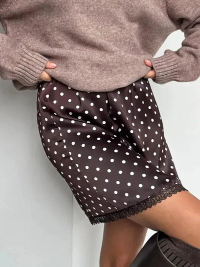 Close-up of chocolate brown satin fabric with white polka dot print, glossy finish detail
