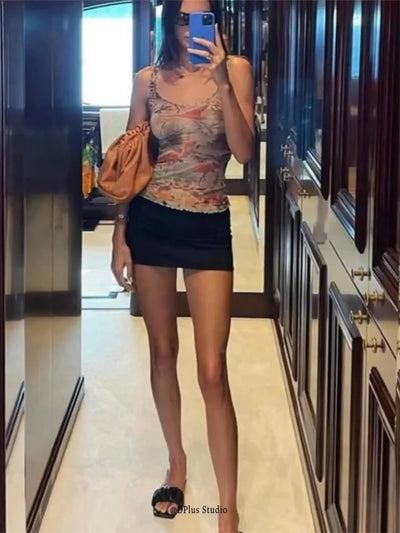 Black satin mini skirt worn with printed tank top and orange bag, mirror selfie