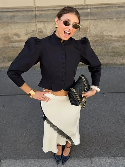 Close-up smiling woman showing asymmetric lace-trim midi skirt with black cropped blouse and chain bag