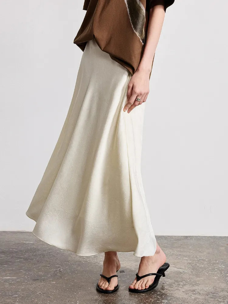 Side view of ivory crinkled satin A-line midi skirt with high waistband and black sandals