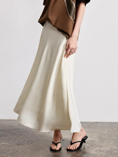 Side view of ivory crinkled satin A-line midi skirt with high waistband and black sandals