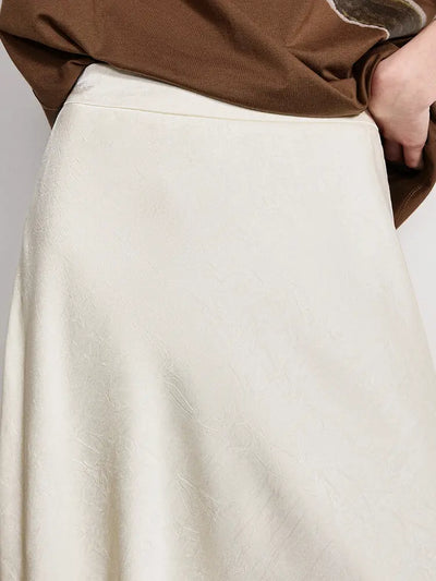Close-up of crinkled glossy ivory satin fabric texture at the skirt waistband