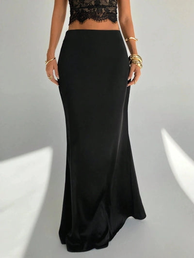 Front three-quarter view of a black high-shine mermaid maxi skirt styled with gold cuff bracelets