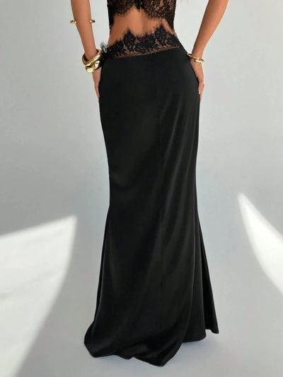 Back view of a black mermaid maxi skirt with a lace crop top, hands on hips, gold jewelry visible