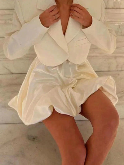 Close-up of ivory bubble-hem satin mini skirt set worn seated, skirt fanning outward