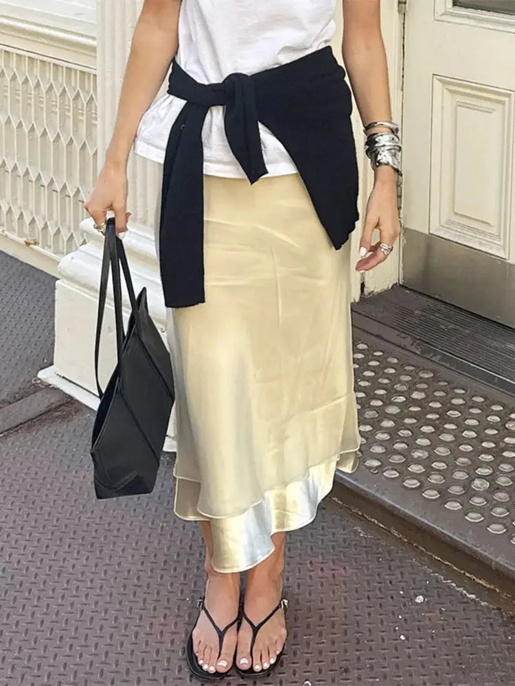Close-up of champagne sheer organza midi skirt with layered satin slip hem and black sandals
