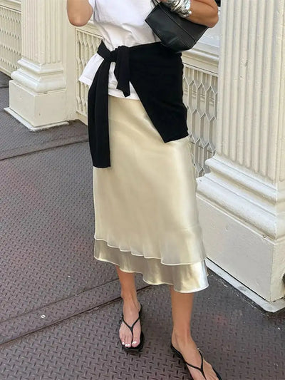 Side view of champagne layered midi skirt with ruffled hem, black sandals, and structured tote