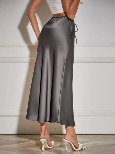 Back view of a gray satin maxi skirt with gathered drawstring waist and flared hem