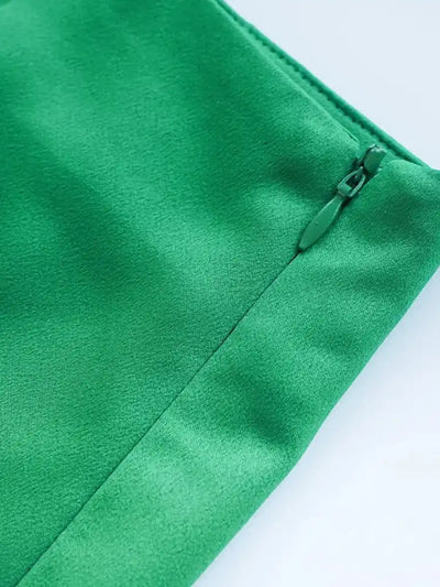 Close-up of emerald green satin skirt showing concealed side zipper detail