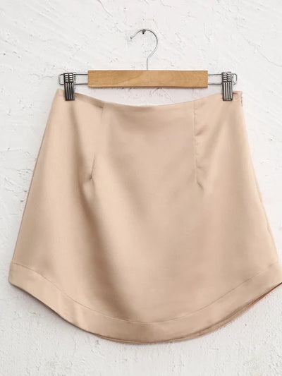 Champagne satin mini skirt on hanger showing smooth finish and structured waistband