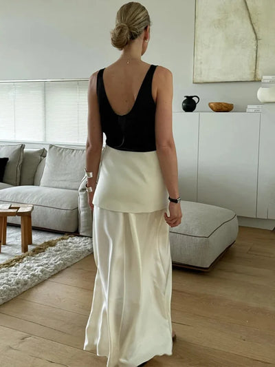 Back view of woman in white double-layer maxi satin skirt with black open-back tank top