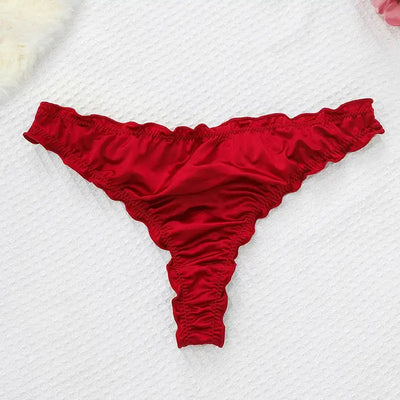 Single red satin thong with ruffled elastic edges laid flat on white textured surface